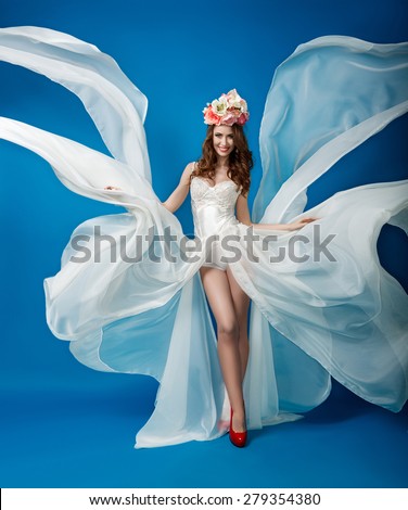 Elegant woman in a flowing white dress on a blue background
