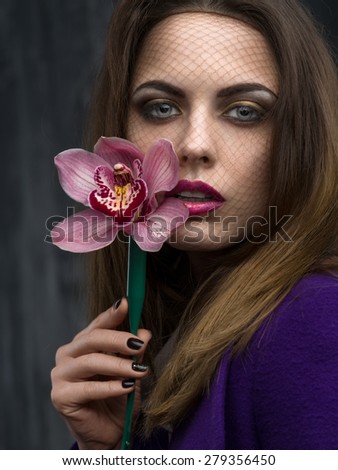 Beautiful woman with a grid on the face with orchid in hands close-up