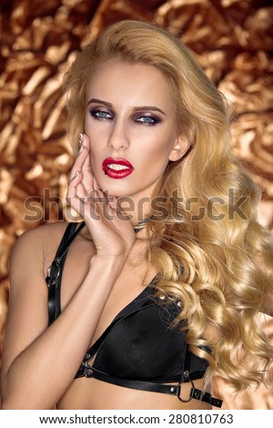 Blonde girl with long wavy hair in black bra on an orange background