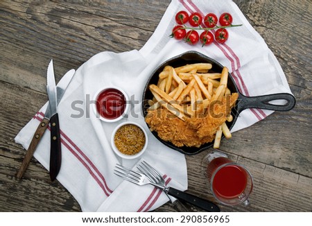 French fries and nuggets in pan on wooden board