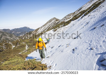 Tourists reaches the top of a snowy mountain in a sunny winter day.