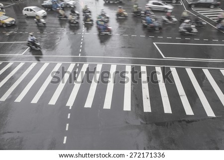 Busy traffic in big city street, blurred motion and zebra crossing abstract in the rain.