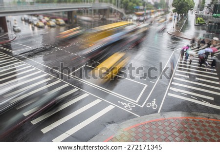 People walking on big city street, blurred motion zebra crossing abstract in the rain.