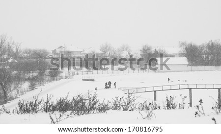 Winter landscape with fields and people enjoying the snow. Snowing makes a lovely grain-like texture
