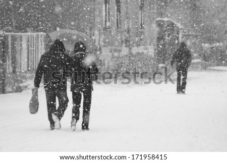 Snowing urban landscape with people passing by