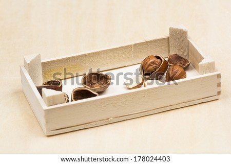 Hazelnuts and shells in a wooden box with wooden background