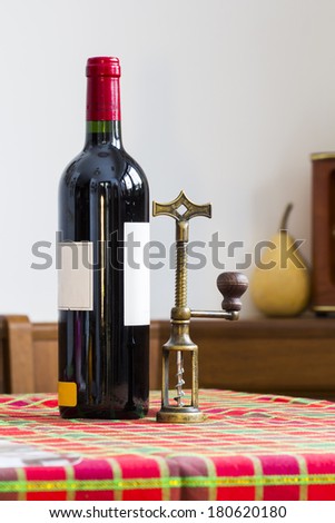 Still life composition with copper corkscrew and bottle of wine on colored table cloth