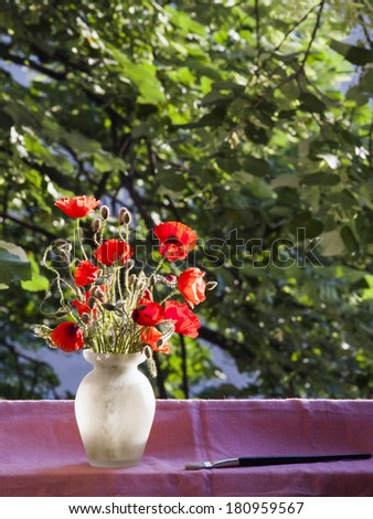 Poppies in the vase, at the window with paintbrush