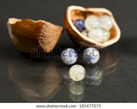 Hazelnut shell with small blue and transparent gemstones on dark background
