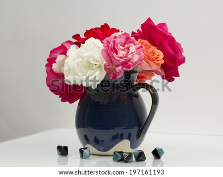 still life composition with colorful, beautiful, delicate roses in a ceramic vase with agate stones near
