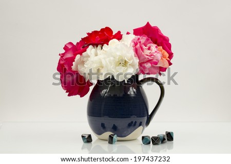 Still life composition with colorful, beautiful, delicate roses in a ceramic vase with agate stones near