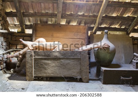 Woman in an wooden scuplted box in the attic with beautiful, moody light