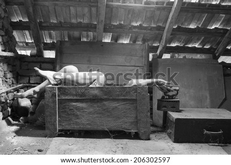 Black and white photo of woman in an wooden scuplted box in the attic with beautiful, moody light