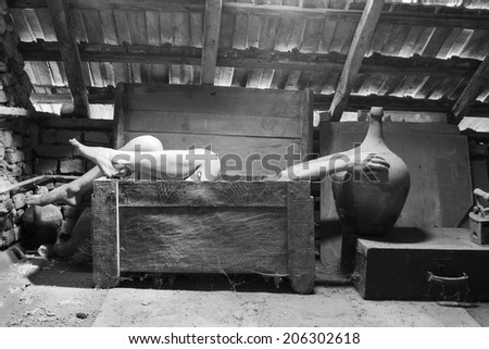 Black and white photo of woman in an wooden scuplted box in the attic with beautiful, moody light