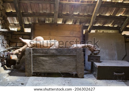 Woman in an wooden scuplted box in the attic with beautiful, moody light