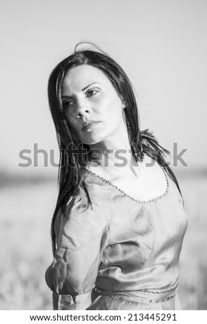 Black and white photo of a brunette girl in the wheat field, looking sad and worried