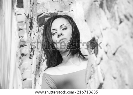Black and white, beautiful, brunette woman in an old, abandoned house, wearing a dress, looking sad and melancholic