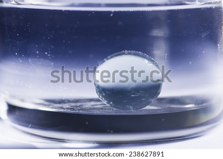 Abstract composition with round glass ball and round transparent vase and water , blur