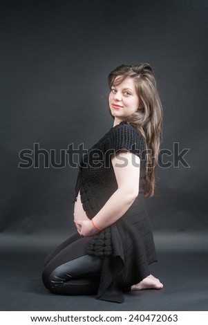 Pregnant woman with dark background, looking happy