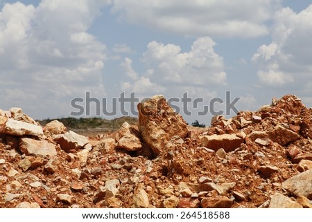 Red soil texture with rocks and sky with clouds