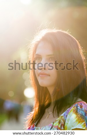 Beautiful girl posing in the park with sun and flares. Image has grain texture visible on maximum size