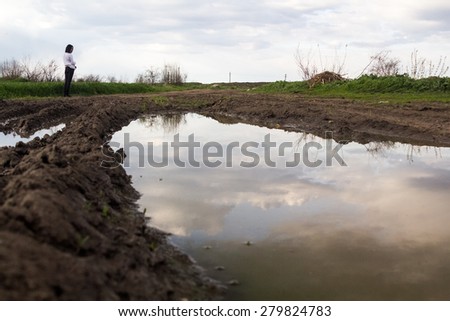 Rural landscape with green fields, soil texture, slops, beautiful sky and girl walking