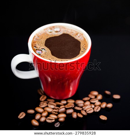 Red cup of coffee with coffee beans and dark background