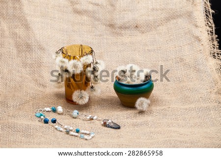 Composition with dandelion seeds, small objects and jewels with burlap texture