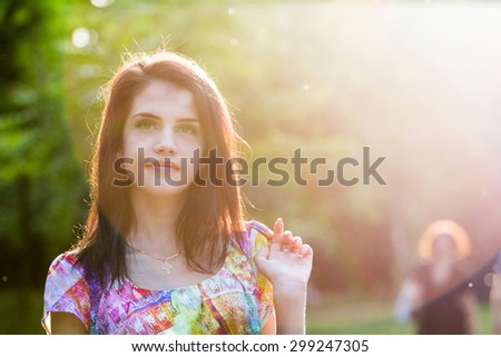 Beautiful girl posing in the park with sun and flares. Image has grain texture visible on maximum size