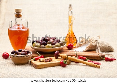 Composition with olive wood, olives, vinegar and spices with burlap texture in the background