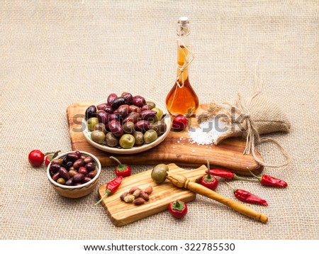 Composition with olive wood, olives, vinegar and spices with burlap texture in the background