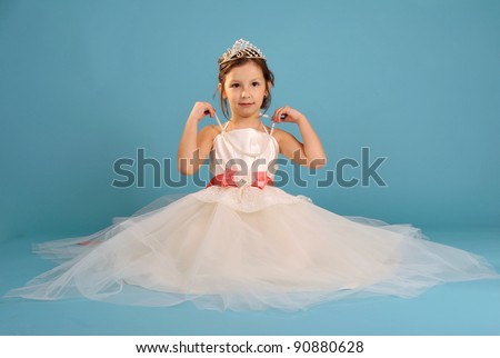 Little beautiful girl sitting in white spruce dress and crown with string of beads in hands