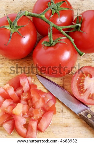 fresh, ripe tomatoes on the vine with chopped tomatoes to the side
