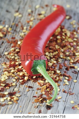 red chilli pepper resting on a bed of crushed chilli flakes