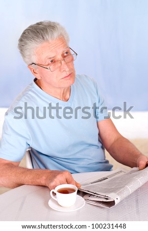cute old man reading newspaper at table