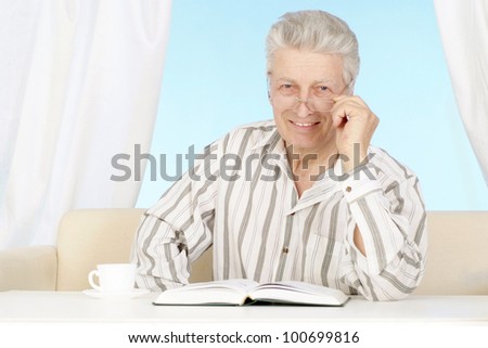 Beautiful old Caucasian man with book sits on a light background