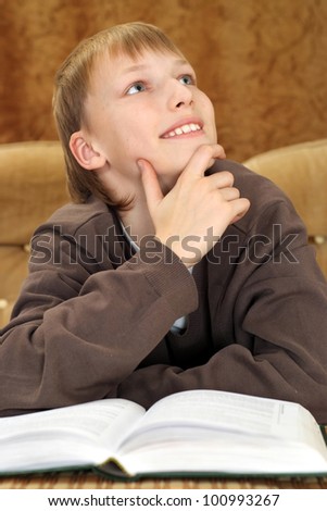 Beautiful Caucasian man sitting on the couch with a book on a brown background