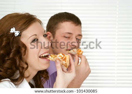 Beautiful Caucasian charming company of two people sit and eat pizza at a cafe