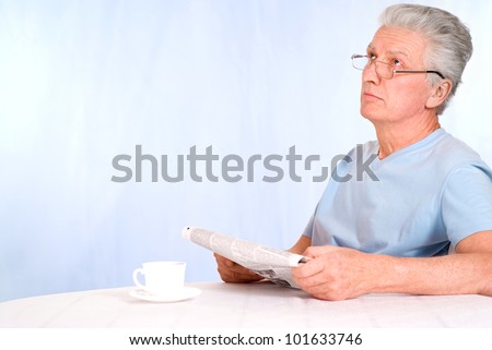 cute old man reading newspaper at table