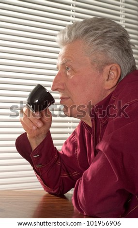 Caucasian aged man with a nice cup on a light background