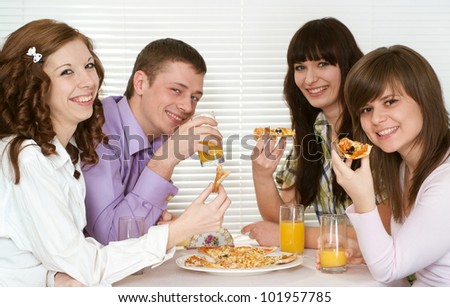 Beautiful charming company of four people sit and eat pizza at a cafe