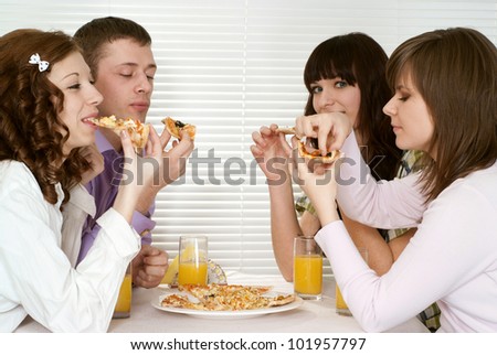 Good Caucasian charming company of four people sit and eat pizza at a cafe