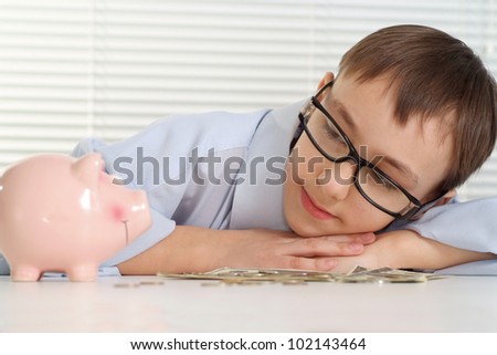 A young Caucasian good business man is looking at a piggy bank on white background