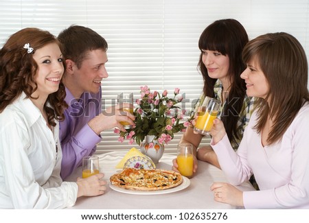 Beautiful Caucasian charming company of four people sit and eat pizza at a cafe