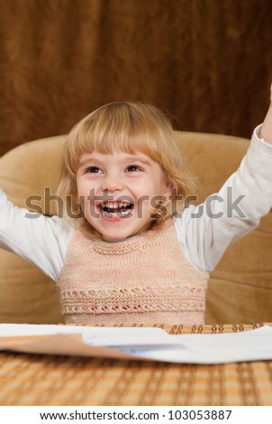 Pretty Caucasian young baby draws a table on a brown background