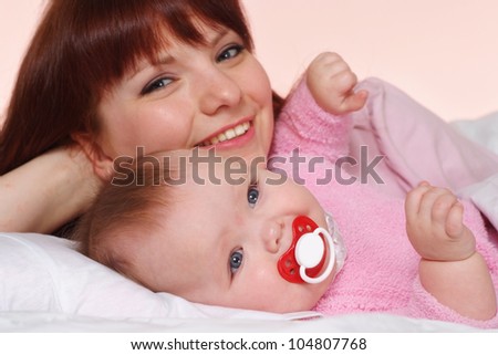 A good Caucasian mummy with her daughter lying in bed on a light background