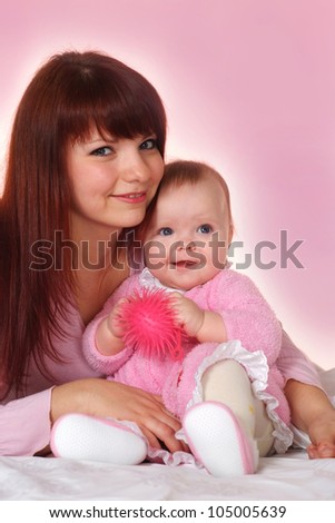 A nice Caucasian mother with her daughter lying in bed on a light background
