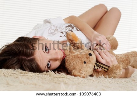 Beautiful woman lying on a carpet with a toy bear
