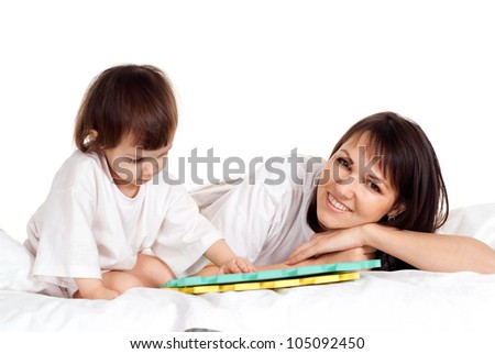 A beautiful mom with her daughter play with a mat in the bed