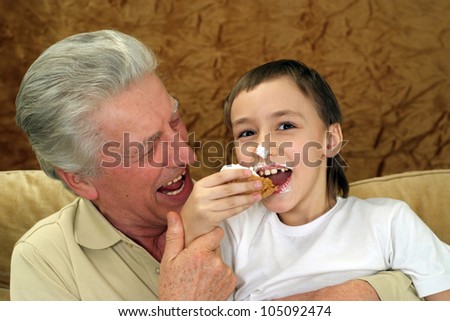 Beautiful nice grandfather with his grandson sitting on the couch on a brown background